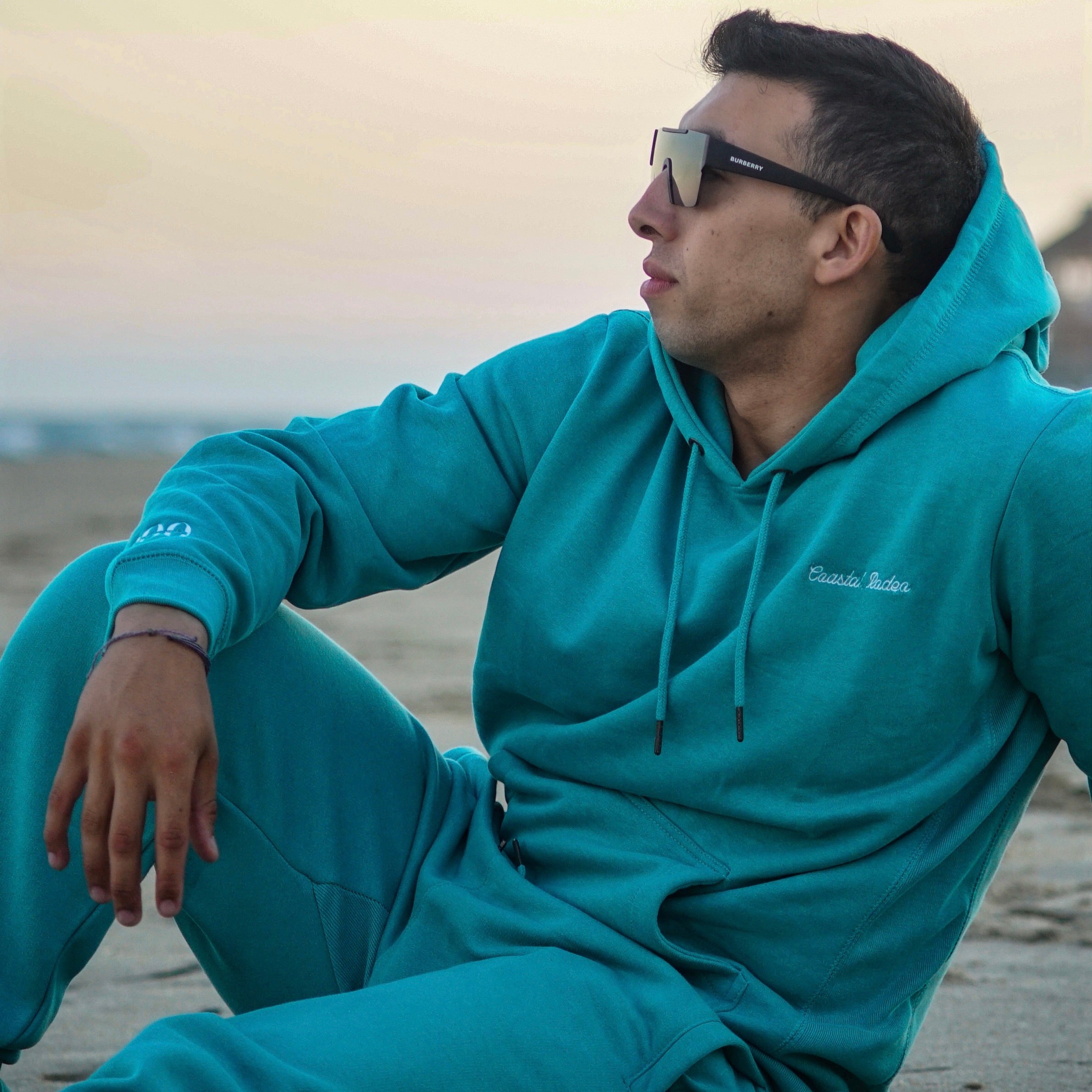 man sitting on beach in a hoodie set